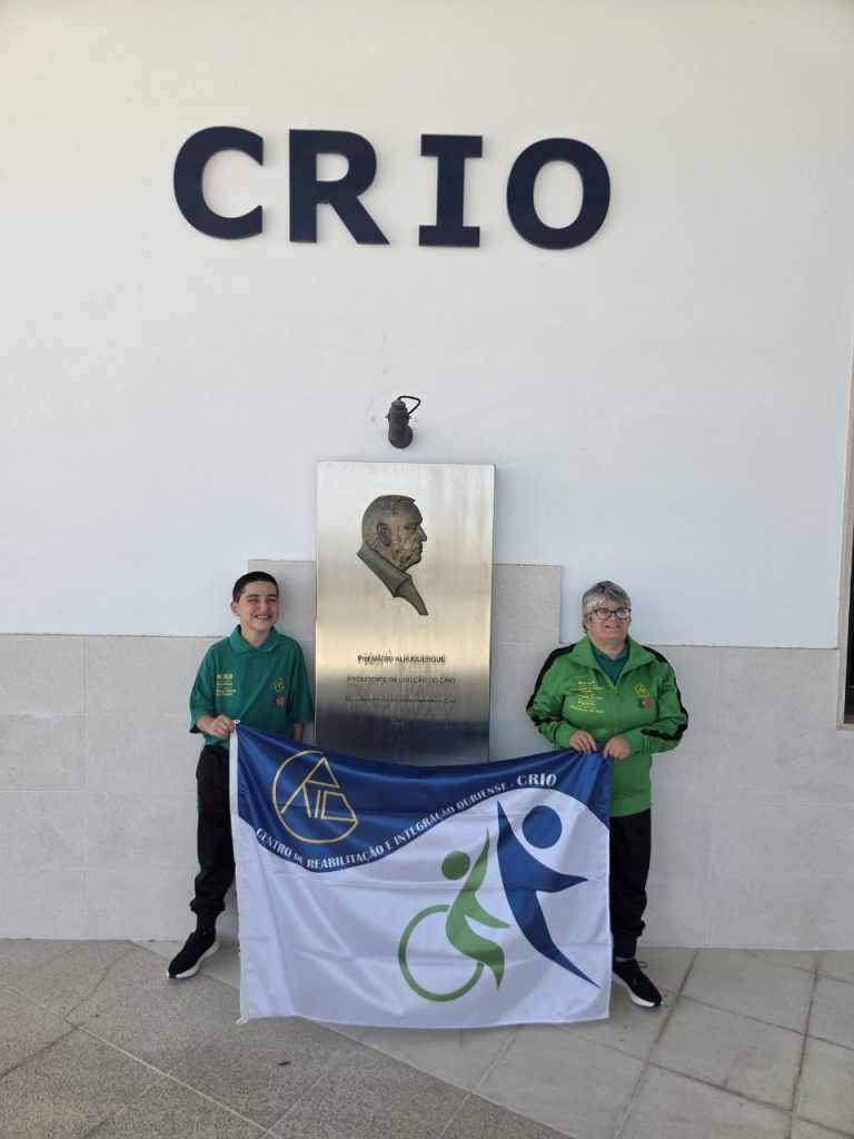 Atletas do CRIO com a bandeira da instituição, junto à placa evocativa do centro
