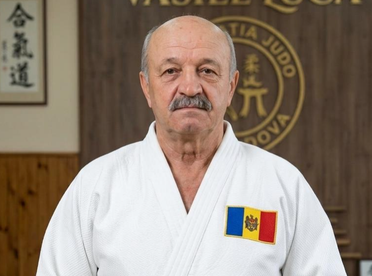 Judoca de judogi branco e cinto preto, num dojo com a inscrição Memorialul Vasile Luca